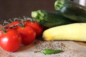 tomatoes, vibrant green zucchini, yellow squash, cumin seeds, and green chili pepper